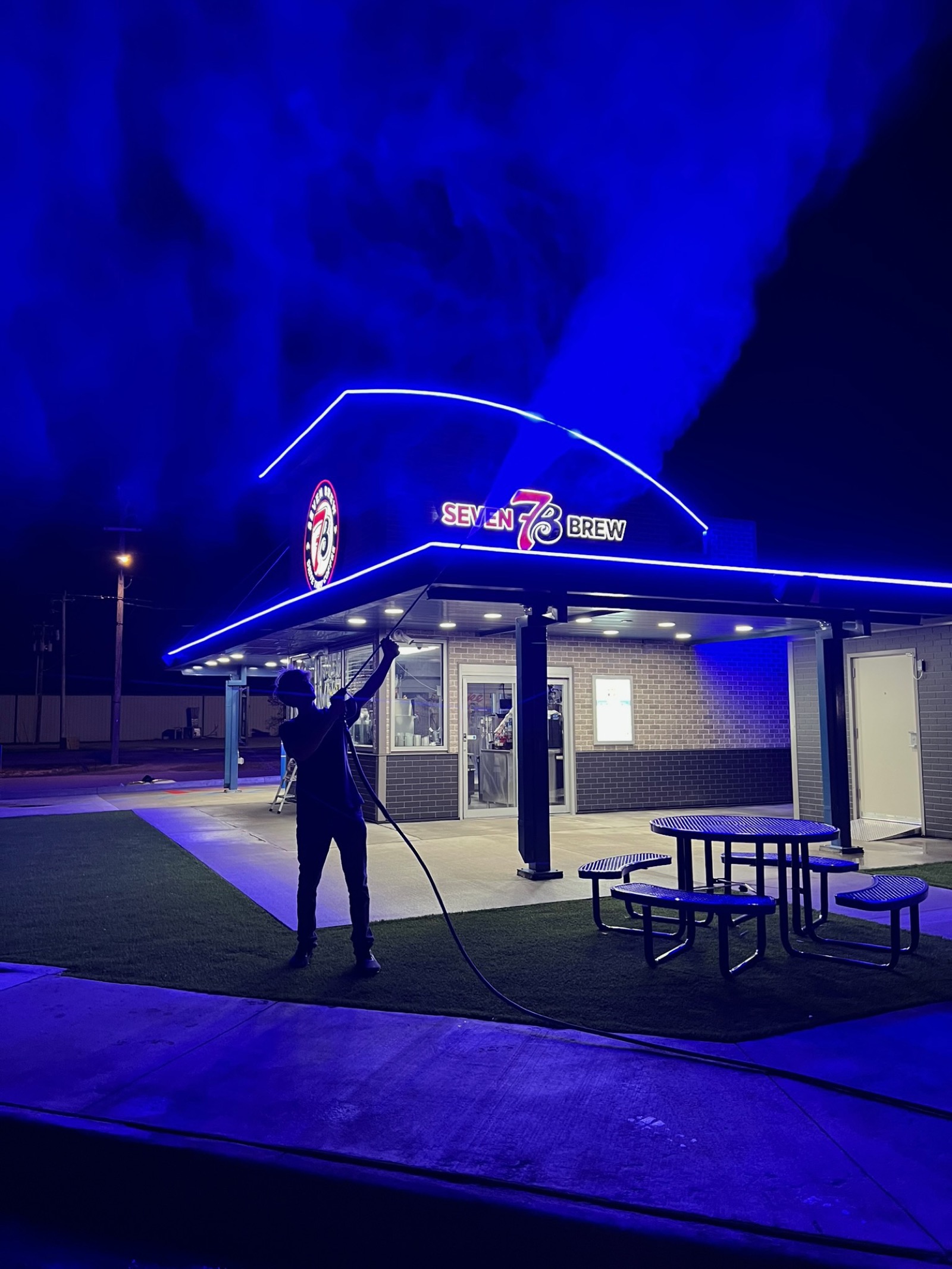 Iron Jet washing a drive-thru at night after closing, spray lit by the stand's lights