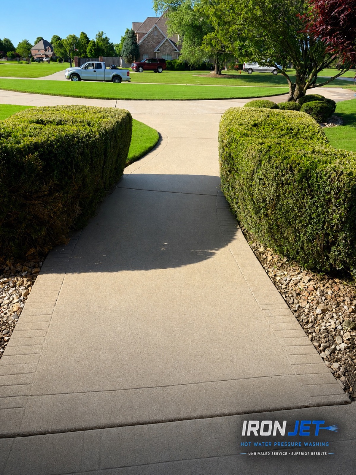 Freshly cleaned residential driveway between trimmed hedges