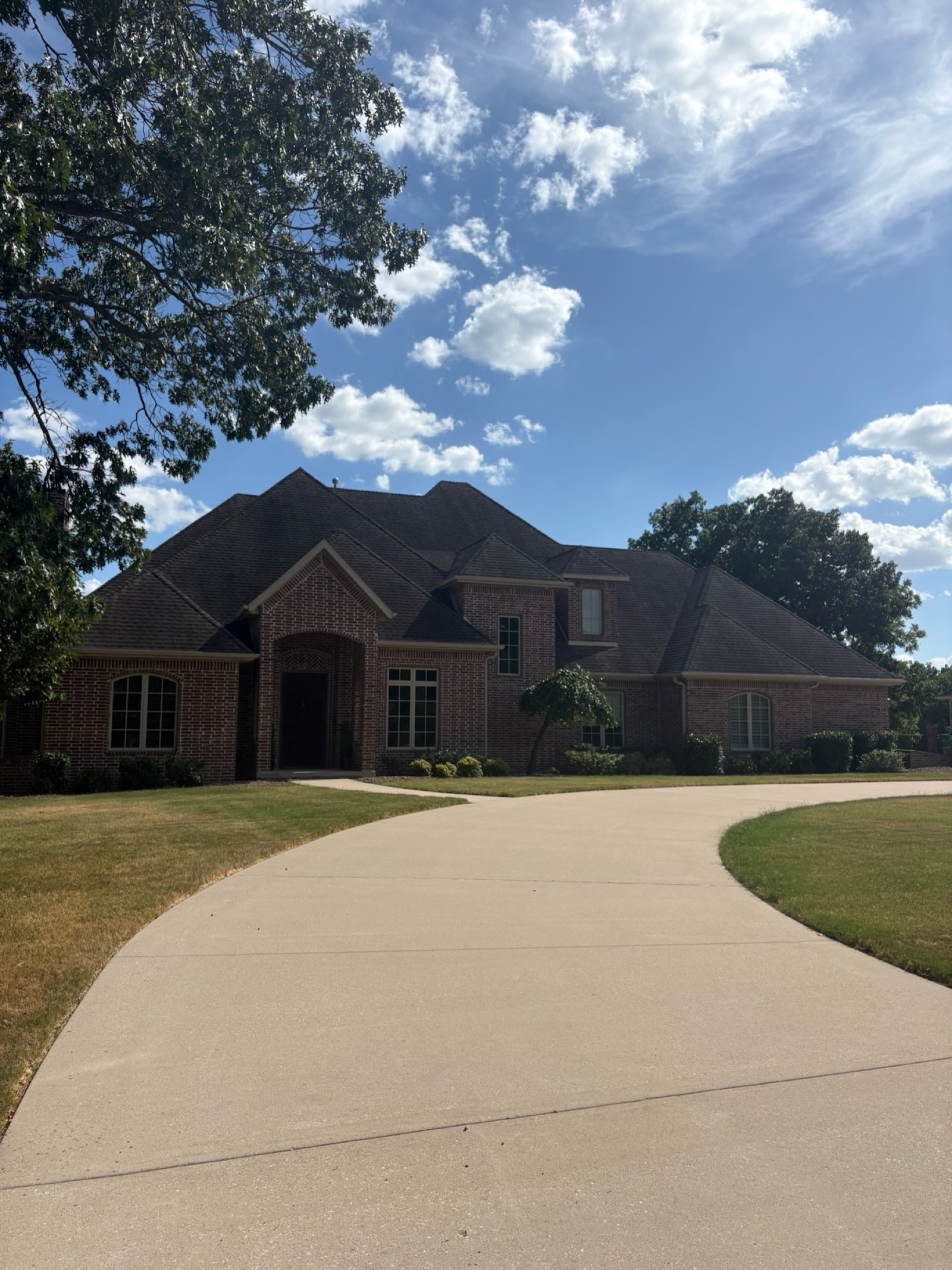 Clean concrete driveway sweeping up to a brick home after hot-water surface cleaning